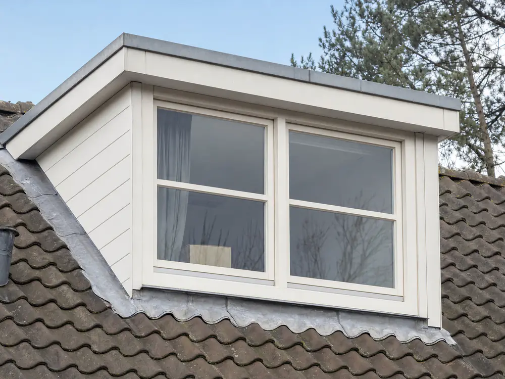 Dakkapel met witte zijwangen, plat dakje en loodwerk langs de zijkanten