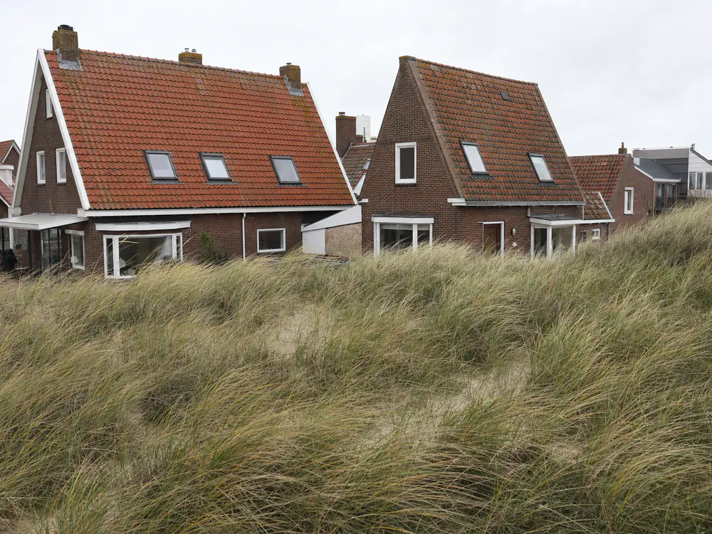 Woningen achter de duinen met vastgezette dakpannen en verweerd zink