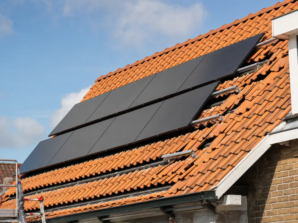 Zonnepanelen op een pannendak, met de haken onder de pannen door